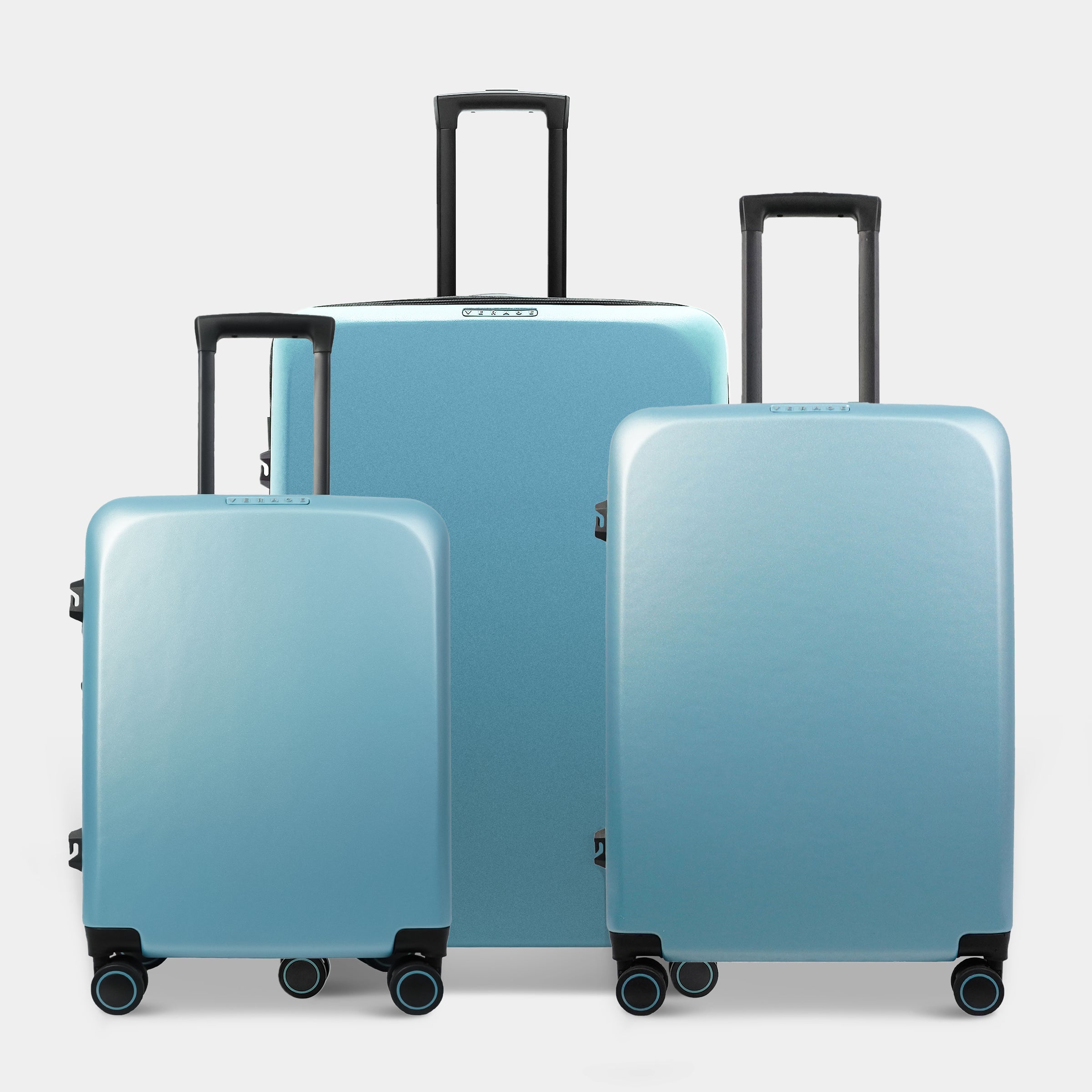 Three pieces of luggage in a gradient blue finish are displayed together. The set includes a large suitcase and two smaller ones, all featuring black trolley handles and wheels for easy mobility.
