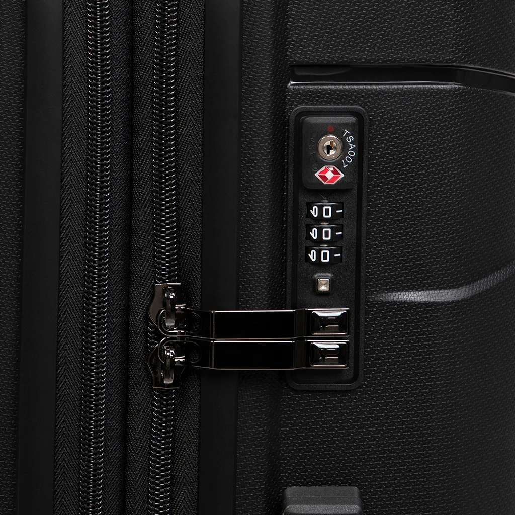 Close-up of a black suitcase featuring a TSA-compatible lock and combination dial. The textured surface enhances durability, while the zipper and latch system ensure secure closure for safe travel.